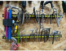 Werkstattwand aus Holz mit zahlreichen aufbewahrten Werkzeugen, darunter verschiedene Schraubendreher, Inbusschlüssel und andere Handwerkzeuge, die an magnetischen Halterungen befestigt sind.