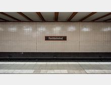 U-Bahn-Station mit cremefarbenen Fliesenwänden; in der Mitte der Wand befindet sich ein Schild mit der Aufschrift „Nordbahnhof“ in einem roten Rahmen. Im Vordergrund sind der Bahnsteig und Schienen sichtbar.
