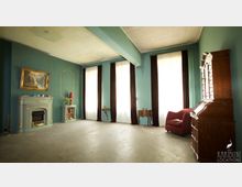 Wohnraum mit türkisfarbenen Wänden und hohen Fenstern, die mit weißen Vorhängen und dunkelroten Vorhangschals dekoriert sind. Der Raum enthält einen antiken Kamin, ein Gemälde, elegante Holzmöbel und eine rote Polstersessel.